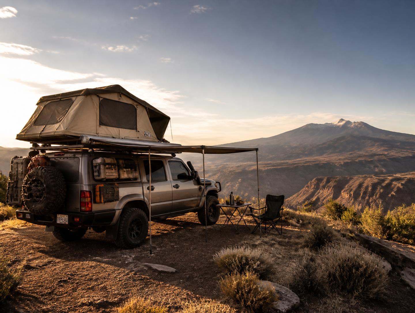 Overland 4x4 build with rooftop tent and awning parked on a high desert overlook at golden hour